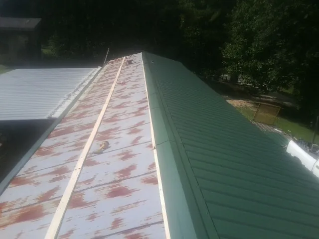 Old rusted panels beside newly installed green metal roofing — Wind Damage Roof Repair by Roofing Brothers in Colts Neck