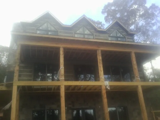Dormers and porch framing on a large log home under construction — Roof Coating work by our crew in Colts Neck