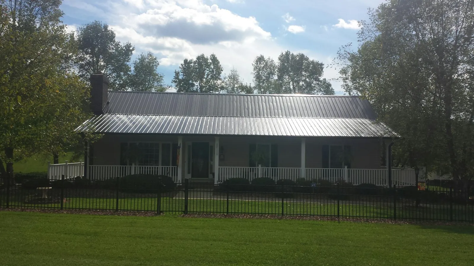 Gray metal roof on a brick ranch with a full width front porch — Gutter Guard Installation work by our crew in Colts Neck
