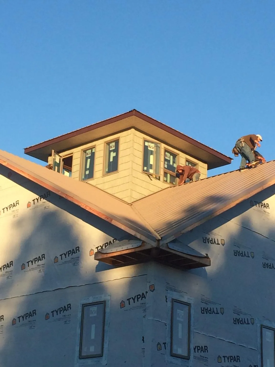 Roofers working around a rooftop cupola on a new metal roof at sunset — Roof Waterproofing in Colts Neck by Roofing Brothers